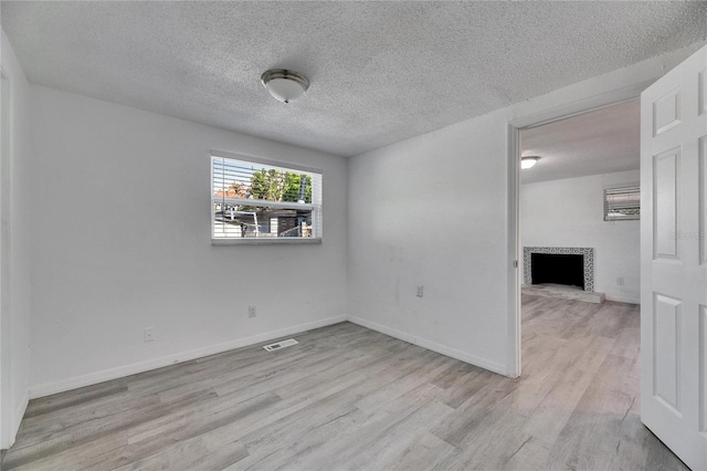 spare room featuring light hardwood / wood-style flooring and a textured ceiling