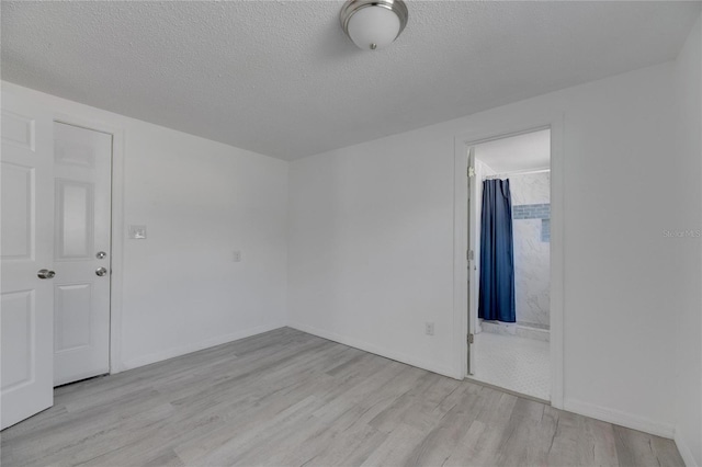 spare room featuring a textured ceiling and light hardwood / wood-style floors