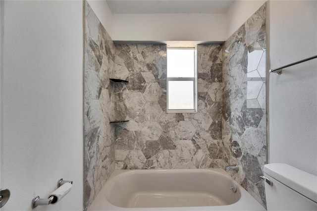 bathroom with tiled shower / bath combo and toilet