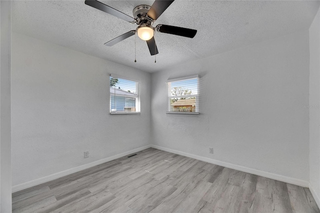 empty room with a textured ceiling, ceiling fan, and light hardwood / wood-style floors