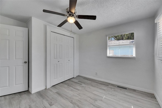 unfurnished bedroom featuring ceiling fan, light hardwood / wood-style flooring, a textured ceiling, and a closet