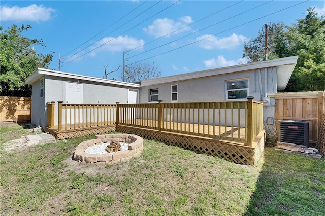 back of property featuring a lawn, a deck, central AC, and a fire pit