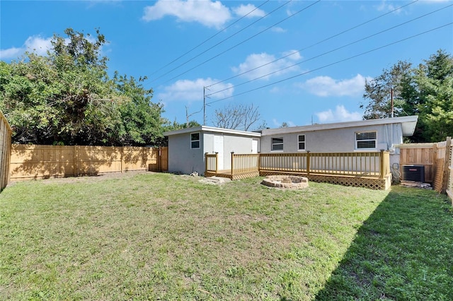 back of house featuring a yard, cooling unit, an outdoor fire pit, and an outbuilding