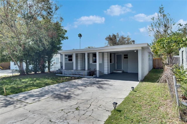 single story home featuring covered porch, a front yard, and a carport