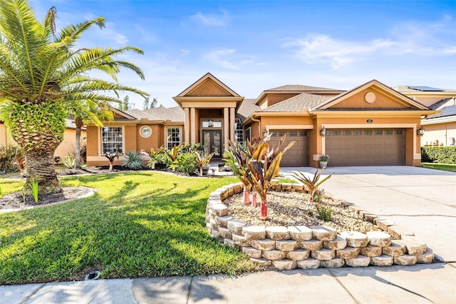 view of front facade featuring stucco siding, a front yard, driveway, and a garage