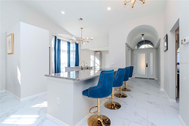 kitchen featuring baseboards, light stone counters, a chandelier, recessed lighting, and marble finish floor