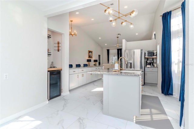 kitchen featuring recessed lighting, appliances with stainless steel finishes, marble finish floor, beverage cooler, and lofted ceiling