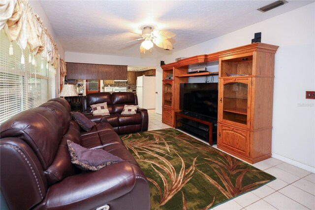 living room featuring light tile patterned floors, baseboards, visible vents, and a ceiling fan