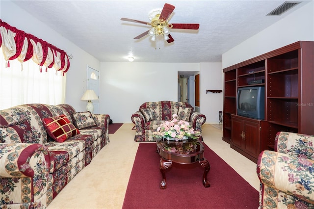 living area with ceiling fan, visible vents, a textured ceiling, and light colored carpet