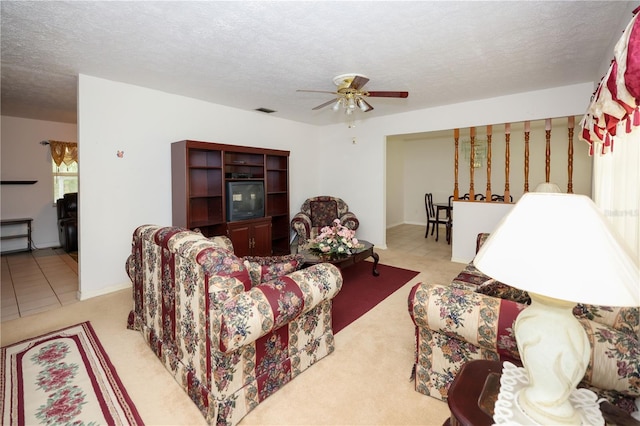 living area with ceiling fan, visible vents, and a textured ceiling