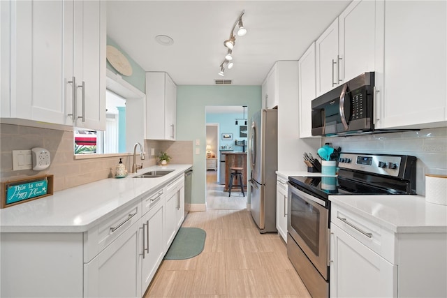 kitchen with tasteful backsplash, white cabinets, appliances with stainless steel finishes, light countertops, and a sink