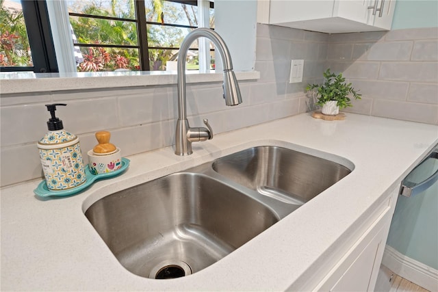 details featuring dishwasher, white cabinets, a sink, and decorative backsplash