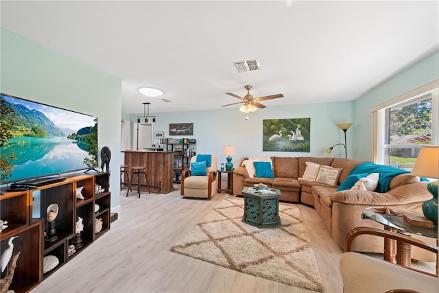 living area with light wood-style floors, visible vents, and ceiling fan