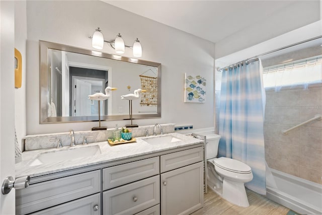 full bathroom with double vanity, toilet, a sink, and wood finished floors