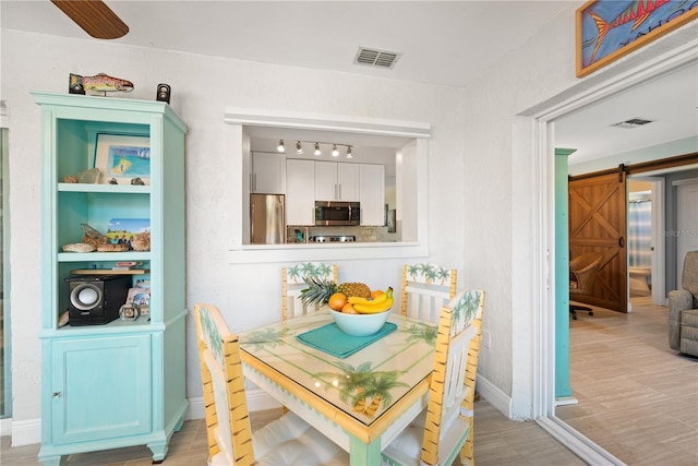 dining space with a barn door, visible vents, and baseboards