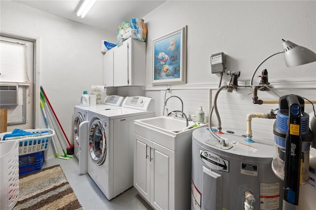 laundry room featuring water heater, wainscoting, independent washer and dryer, and cabinet space