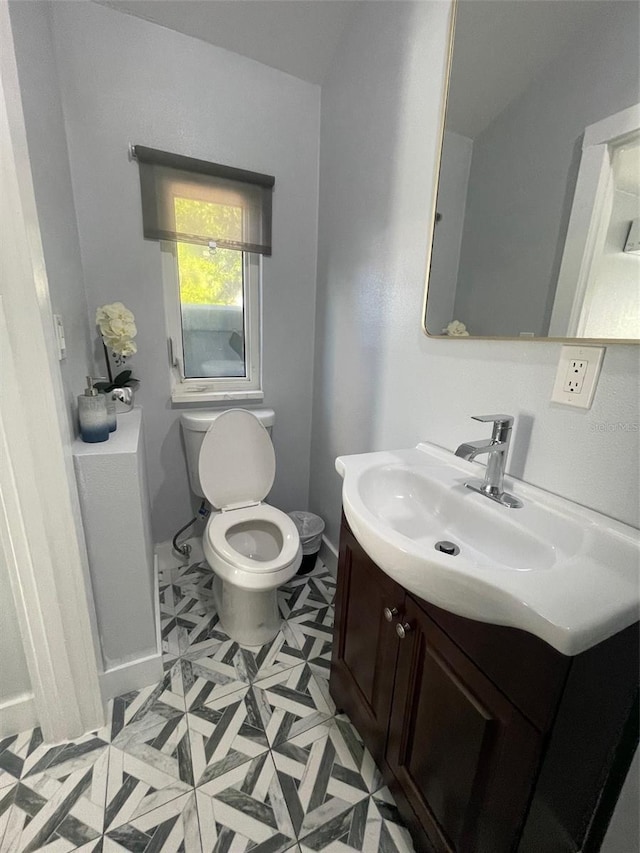 half bath featuring toilet, tile patterned floors, baseboards, and vanity