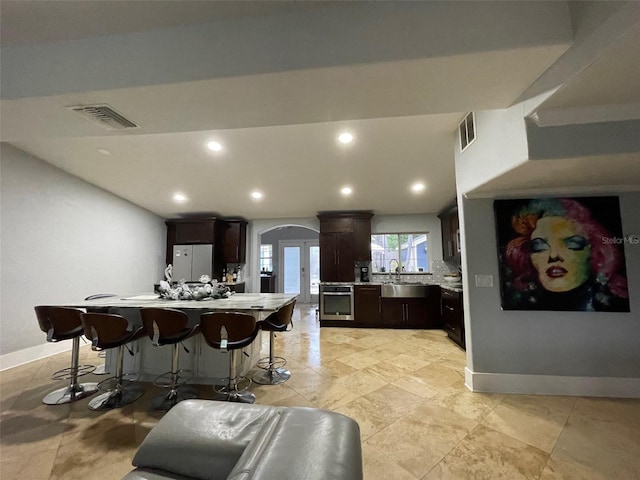 kitchen with light countertops, freestanding refrigerator, visible vents, and dark brown cabinets