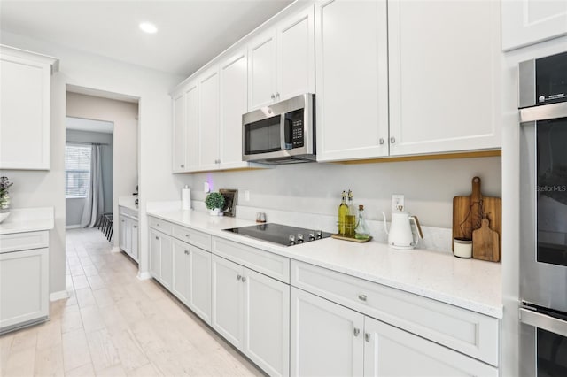 kitchen with recessed lighting, light wood-style flooring, appliances with stainless steel finishes, white cabinetry, and light stone countertops