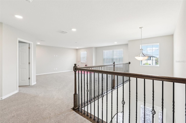 hall with light carpet, a wealth of natural light, and baseboards