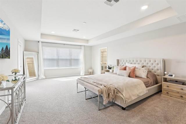 carpeted bedroom featuring a tray ceiling and visible vents