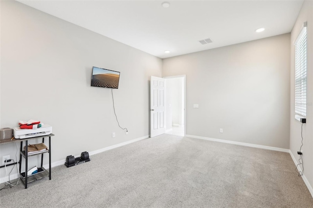 carpeted empty room with visible vents, baseboards, and recessed lighting