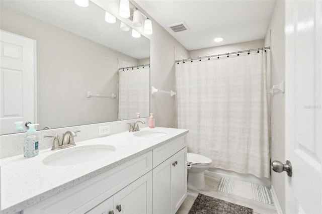 bathroom with double vanity, visible vents, toilet, and a sink