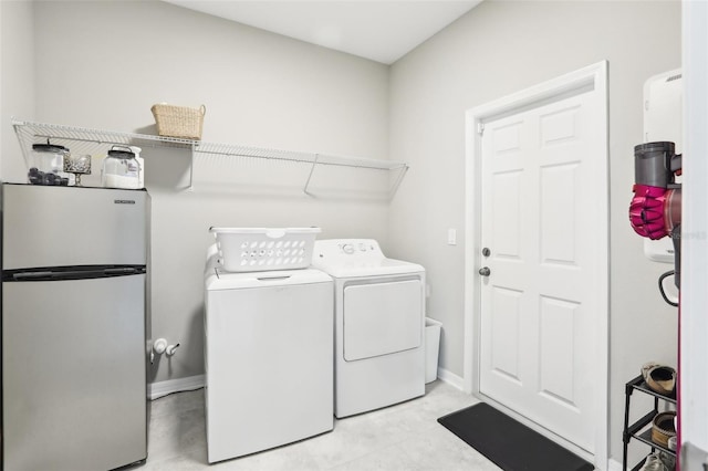 clothes washing area with laundry area, baseboards, and separate washer and dryer