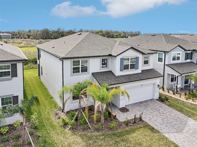 view of front of home featuring an attached garage, a front yard, decorative driveway, and roof with shingles