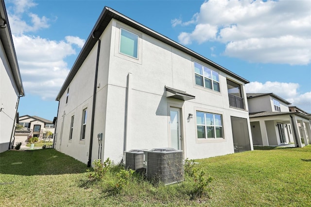 rear view of property featuring cooling unit, a lawn, and stucco siding