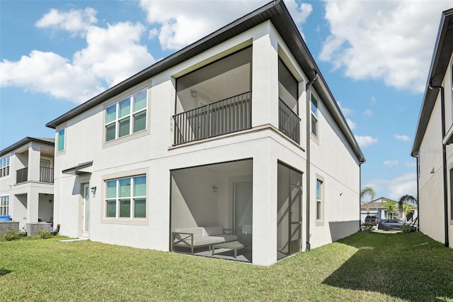 rear view of house featuring a lawn and stucco siding