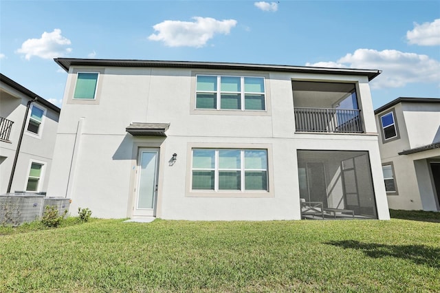 back of house featuring a yard, a balcony, a sunroom, and stucco siding