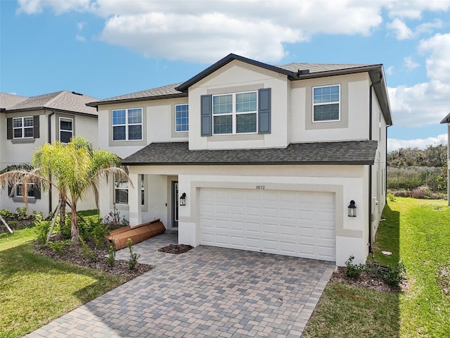 view of front of home with an attached garage, a front yard, decorative driveway, and stucco siding