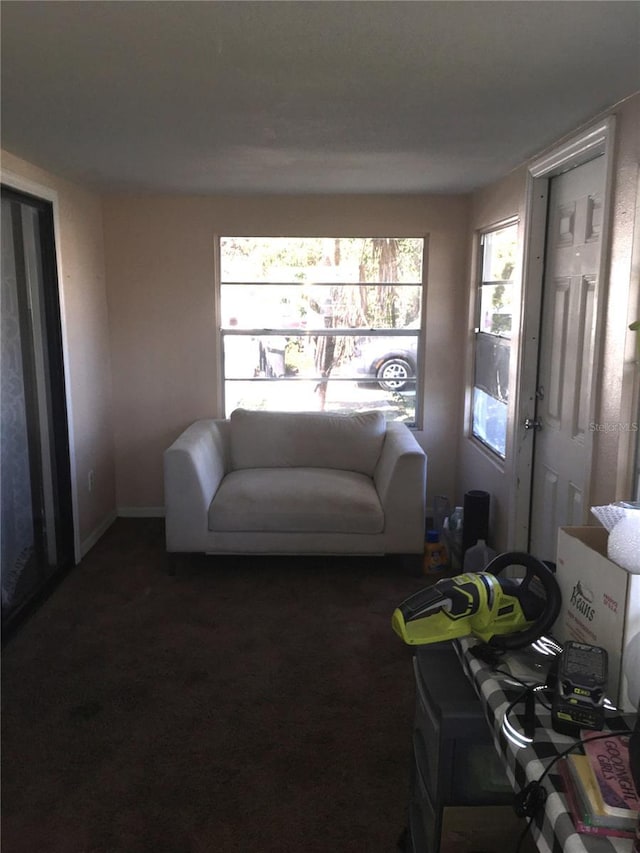 living area with dark carpet and baseboards