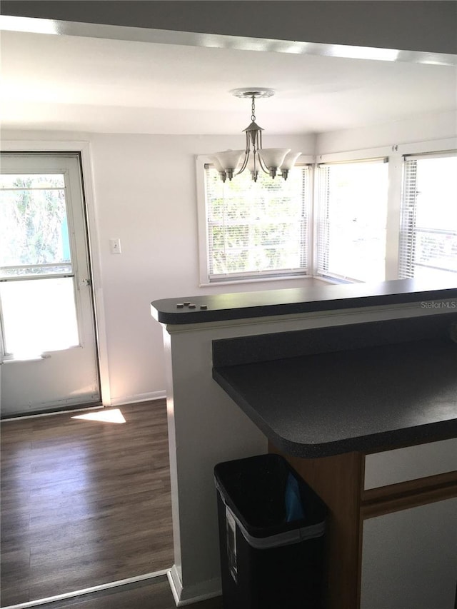 unfurnished dining area featuring a chandelier, dark wood-style flooring, and a healthy amount of sunlight