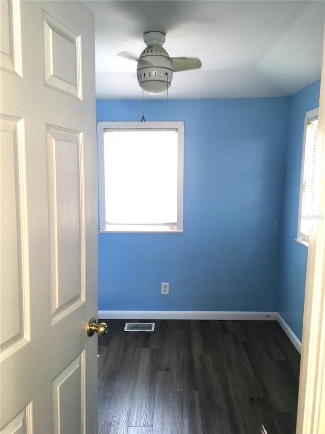 empty room featuring ceiling fan, wood finished floors, visible vents, and baseboards