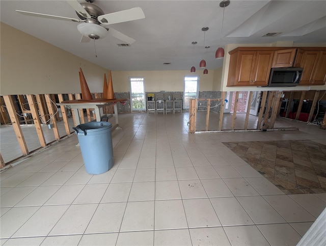 interior space with light tile patterned floors, visible vents, stainless steel microwave, and brown cabinets