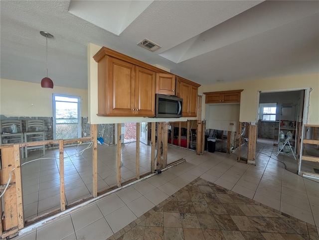 kitchen featuring hanging light fixtures, a healthy amount of sunlight, visible vents, and light tile patterned flooring