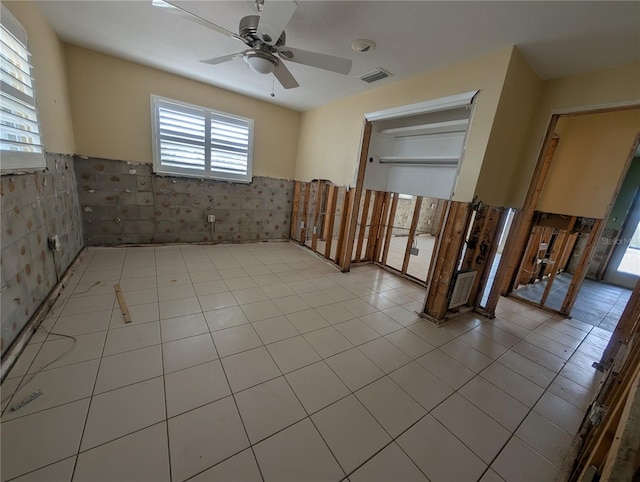 unfurnished room featuring a ceiling fan, a wainscoted wall, visible vents, and light tile patterned flooring