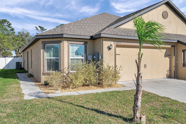 view of front of home with a front yard, central AC unit, and a garage