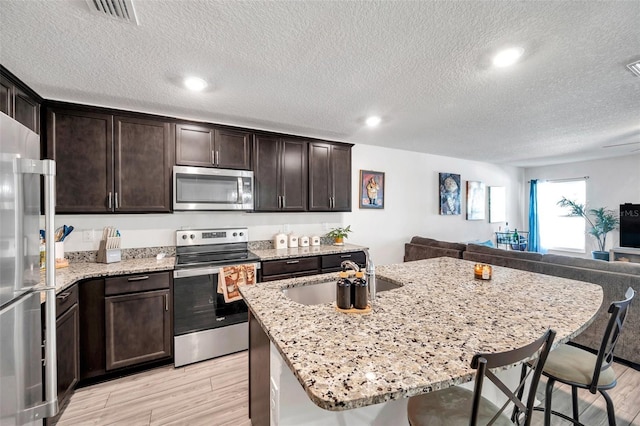 kitchen featuring an island with sink, a breakfast bar, stainless steel appliances, and sink