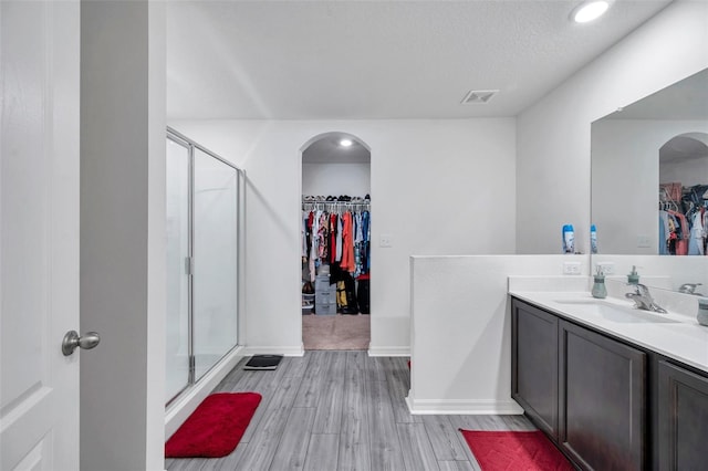 bathroom featuring hardwood / wood-style flooring, a textured ceiling, vanity, and a shower with door