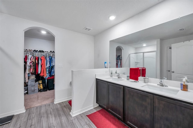 bathroom featuring hardwood / wood-style flooring, vanity, an enclosed shower, and a textured ceiling