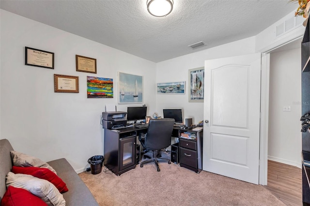 carpeted home office with a textured ceiling