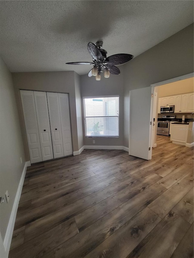 unfurnished bedroom featuring a closet, a textured ceiling, baseboards, and wood finished floors