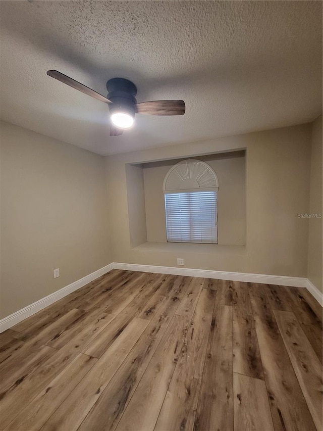 spare room with baseboards, a textured ceiling, a ceiling fan, and wood finished floors