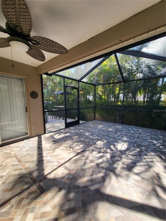 view of patio with a ceiling fan and glass enclosure