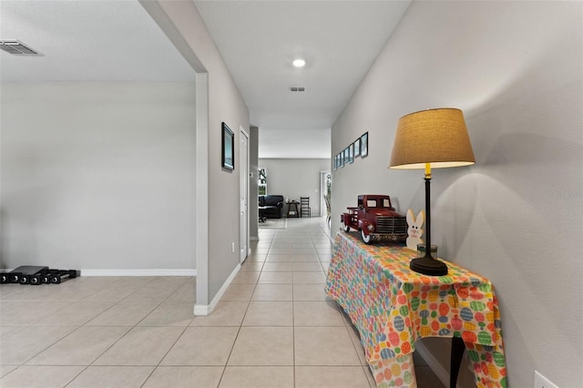 hallway featuring light tile patterned flooring, visible vents, and baseboards