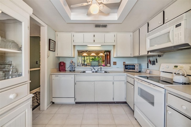 kitchen with white appliances, a sink, white cabinets, light countertops, and a raised ceiling