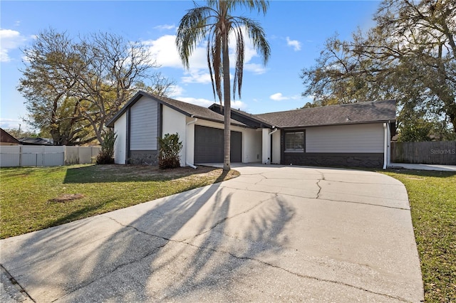 mid-century inspired home with a front yard, concrete driveway, fence, and an attached garage